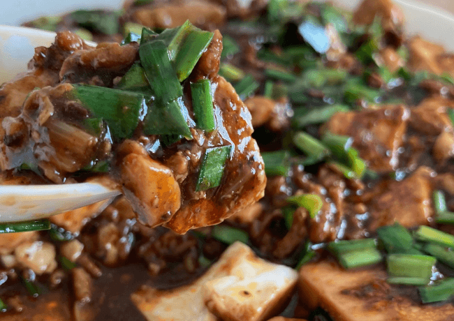 黒麻婆豆腐をレンゲですくっている