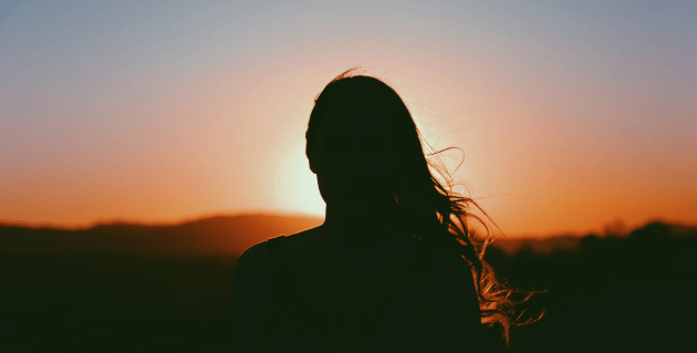 夕日を眺める女性の後ろ姿